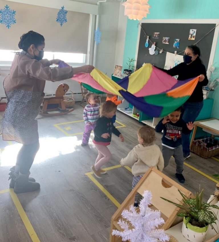 Guides lift a rainbow parachute over toddlers during music and movement